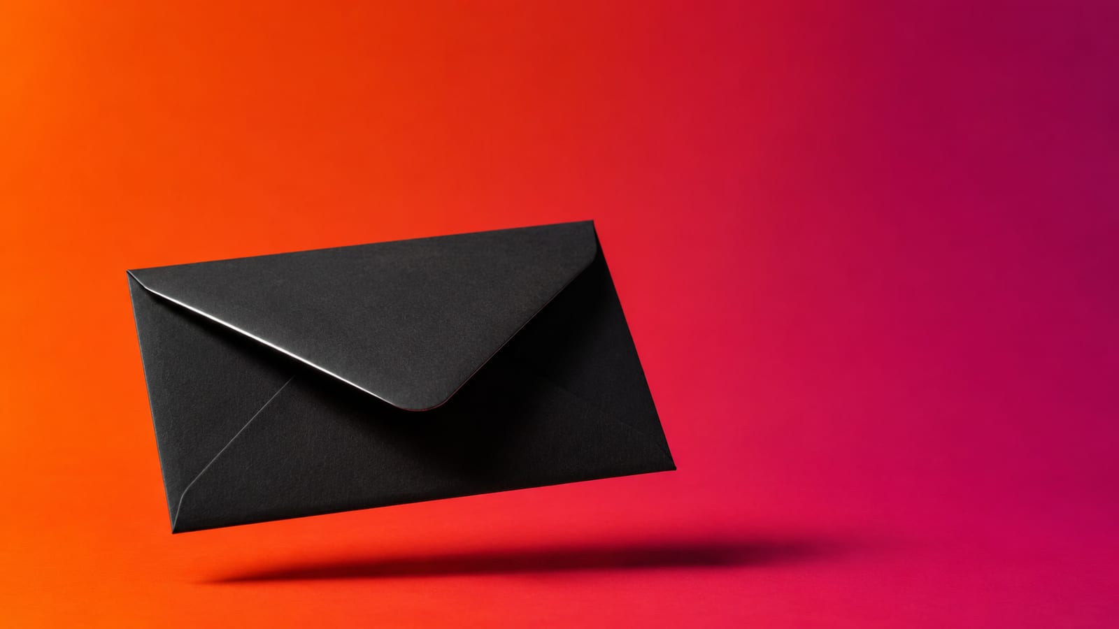 A sealed matte-black envelope floating above a hot orange and magenta backdrop with one hard shadow