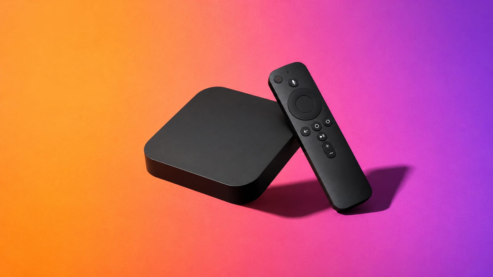 Matte-black streaming box with its remote leaning against it on an orange, magenta and violet studio background
