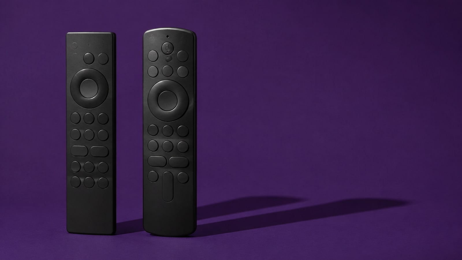 Two different unbranded television remotes on a deep violet background