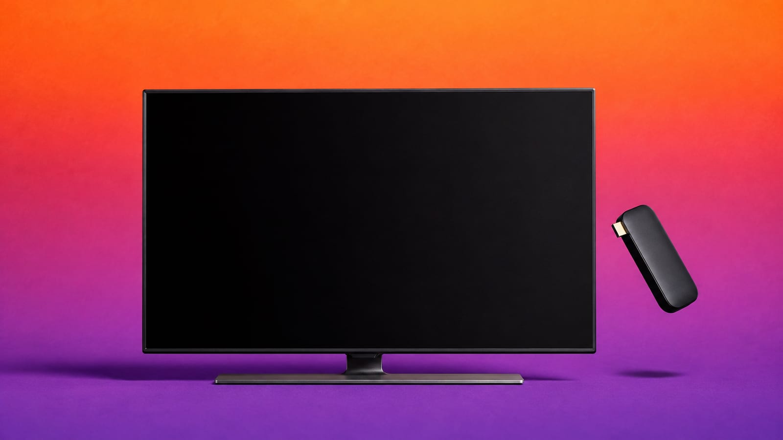 Matte-black television with a small streaming stick floating beside its HDMI port on an orange, magenta and violet studio background